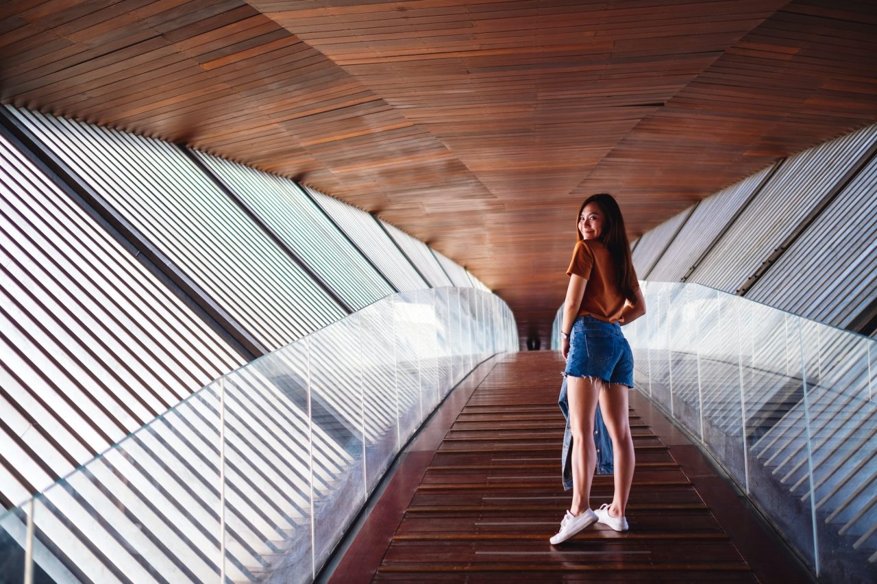 a young asian woman walking inside a modern wooden building